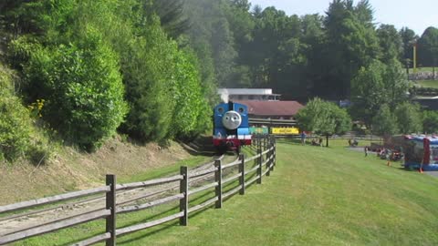 Thomas la locomotora azul rodando a lo largo de la vía férrea con un tren