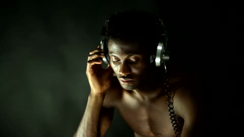 Shirtless man listening to music with retro headphones