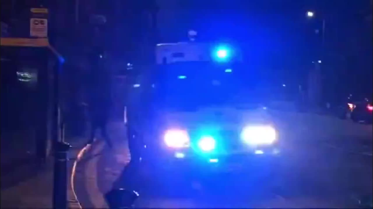 Liverpool, England — A police vehicle swerves and nearly hits people on the road