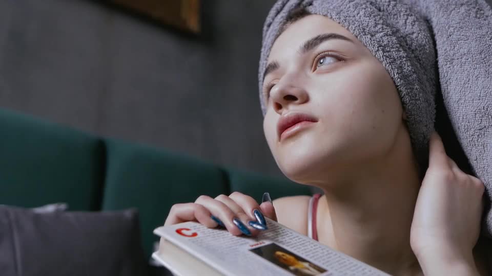 Close-up Footage of a Woman Looking Afar While Holding a Book