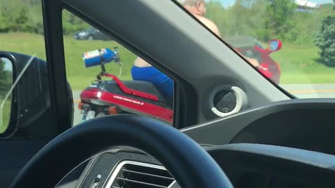 Shirtless Man Moseys Down Highway on Motorcycle