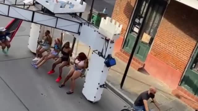 Person in Balcony Films a Bicycle Dragging Frame With Sleeping Net, Cozy Roof and 4 Swings Attached