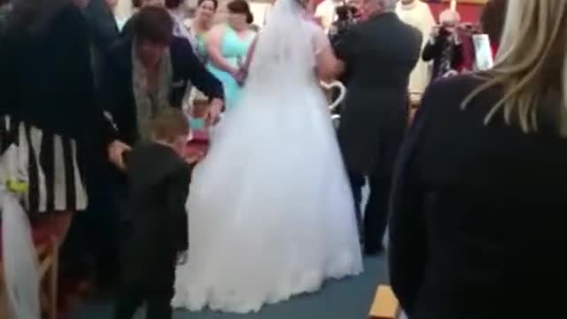 Niño se zambulle sobre el vestido de una novia durante la ceremonia