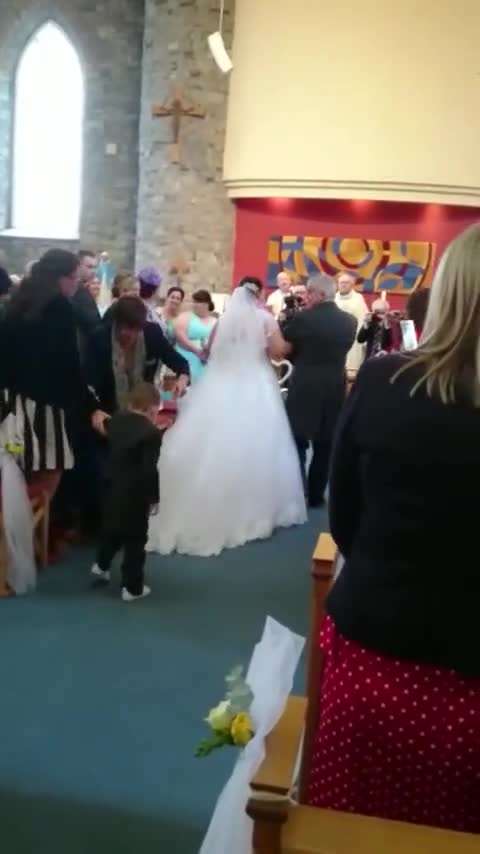 Niño se zambulle sobre el vestido de una novia durante la ceremonia