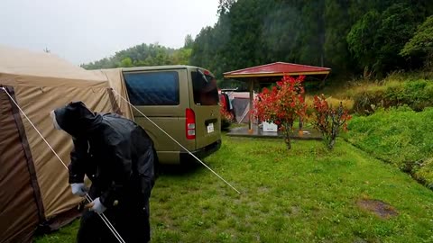 A family with three people camping in the rain