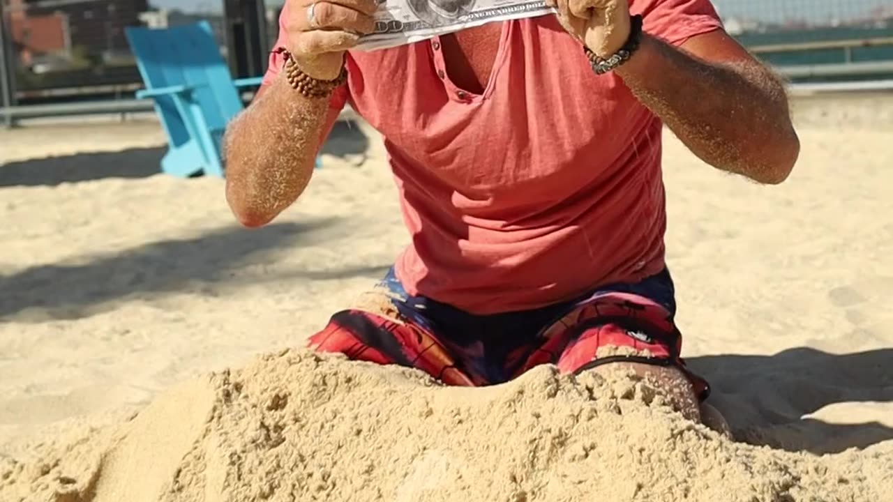 A Man Digging Money From The Sand