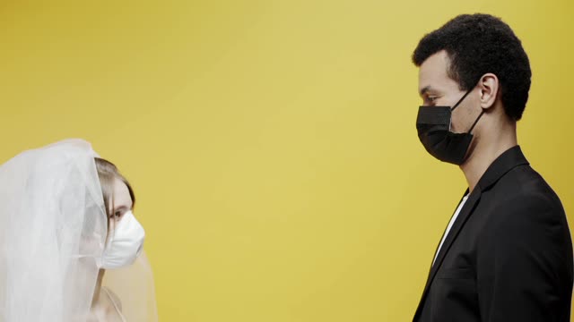 A Newly Wed Couple Kissing While Wearing Face Masks