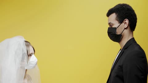 A Newly Wed Couple Kissing While Wearing Face Masks