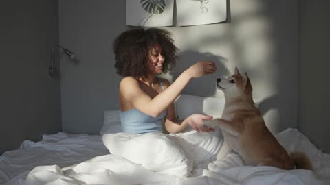 Teasing her pet dog with food while in bed