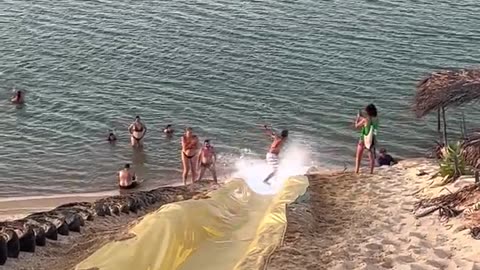 Man Surfs Down Waterslide and Somersaults Into Water