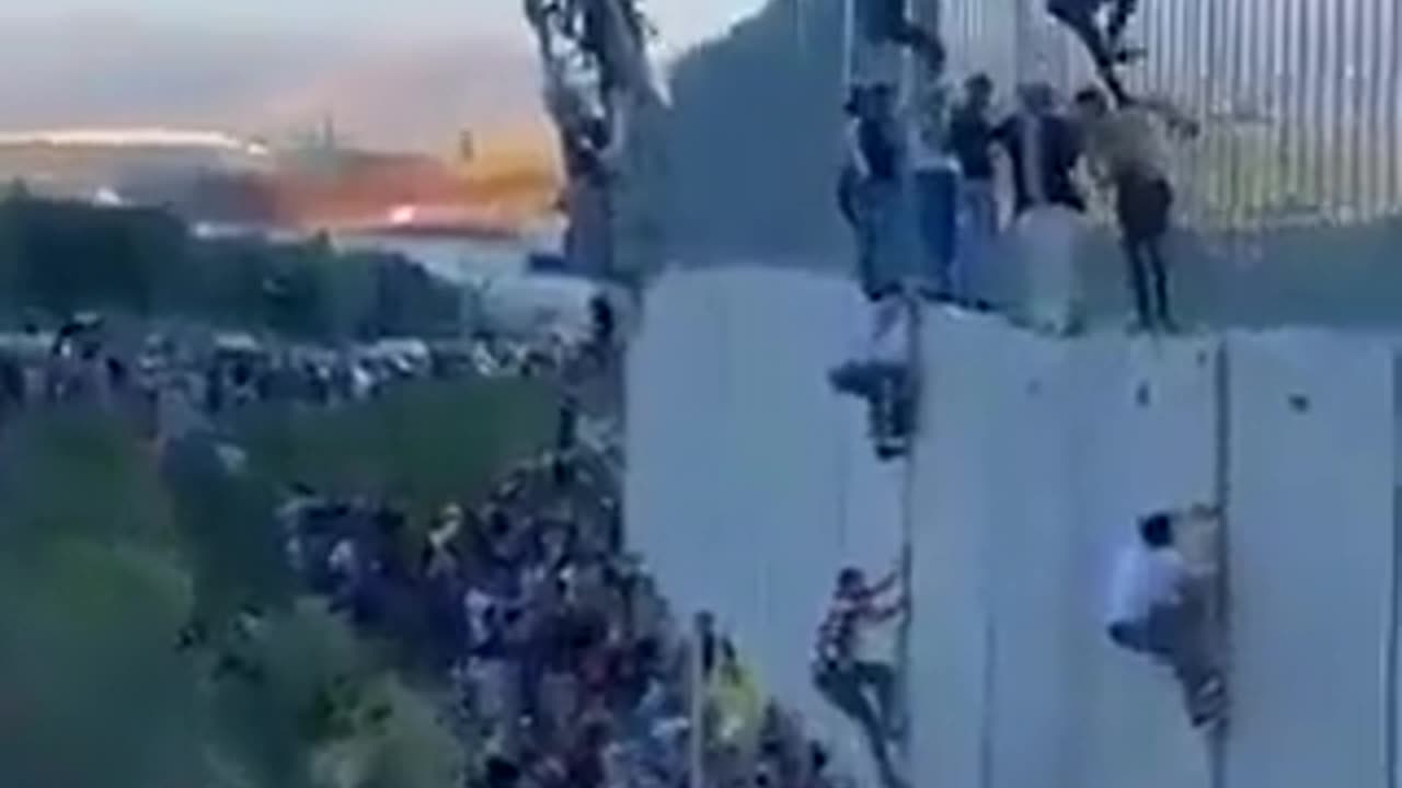 Lebanese people climbing the Israeli barrier