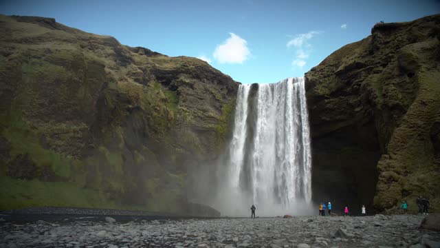 People At The Base Of Large Waterfall