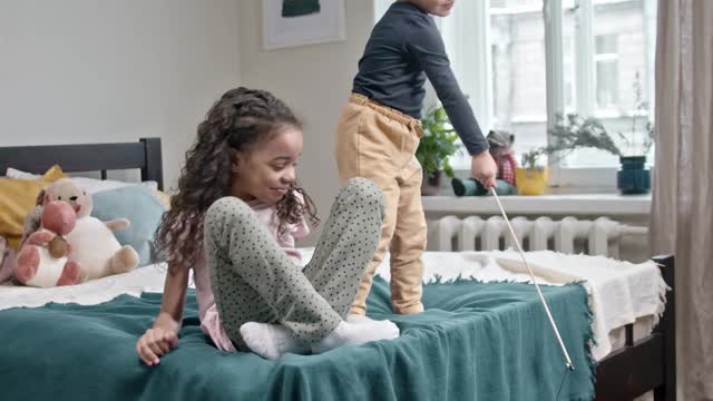 Kids Playing Catch The Bait With Their Cat In The Bedroom