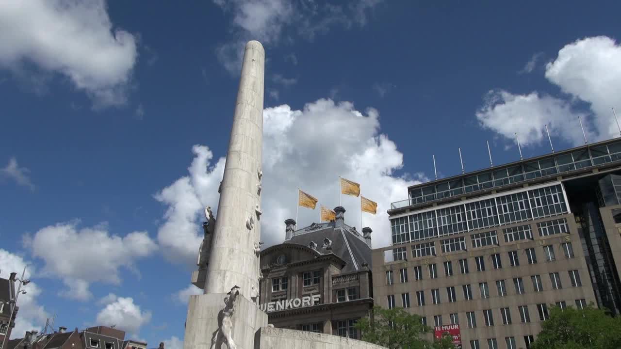 Netherlands Amsterdam dam square obelisk and flags against clouds 2