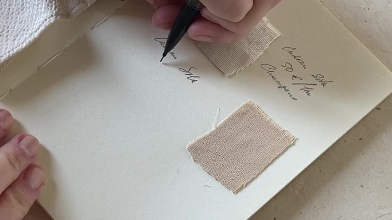 A Person Labeling Fabric Samples on a Swatch Book