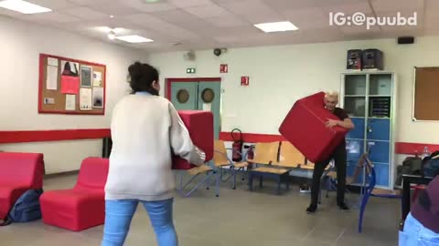 Guy and girl run at each other with red block chairs girl runs into wall