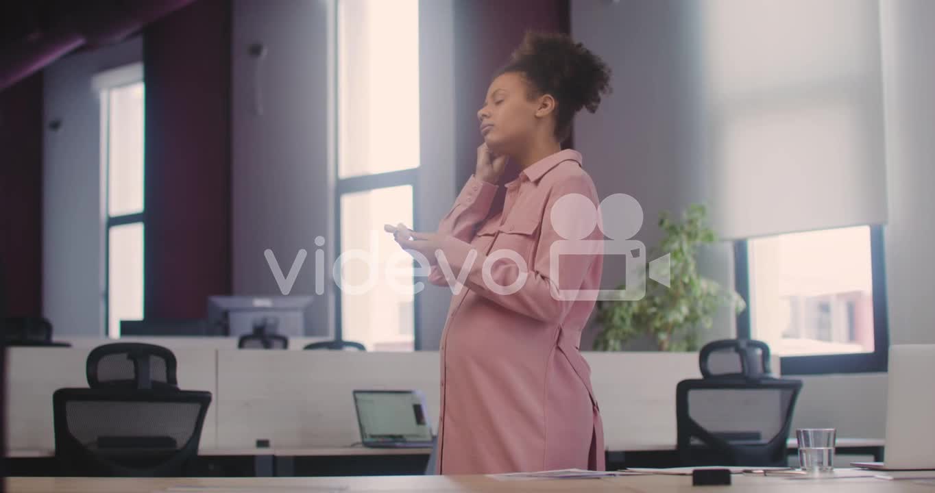 Happy Pregnant Woman Wearing Wirless Earphones And Dancing In The Office