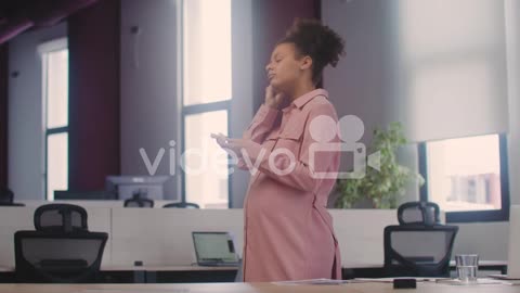 Happy Pregnant Woman Wearing Wirless Earphones And Dancing In The Office