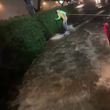 Guy surfing in flood waters pulled by car