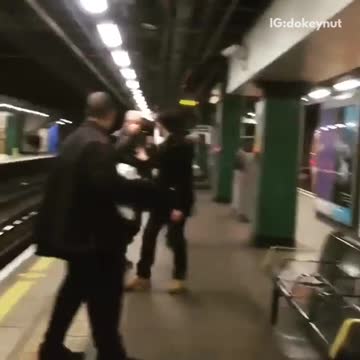 Two bald guys black jacket blue jacket fighting subway station platform