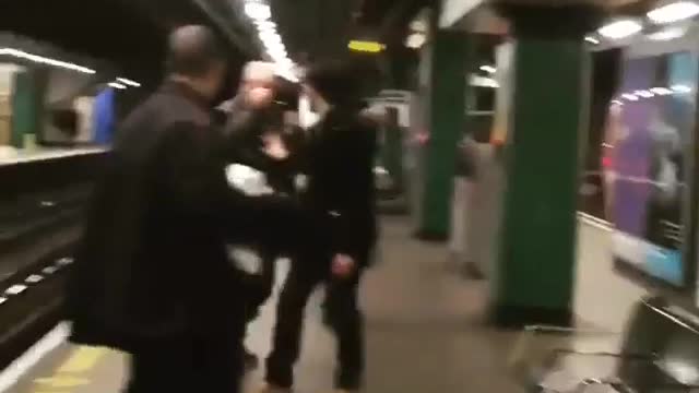 Two bald guys black jacket blue jacket fighting subway station platform