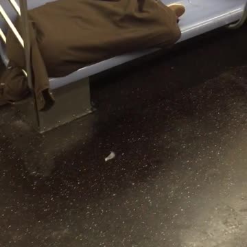 Man sleeps covered in own coat on side on subway