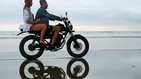 Couple riding a motorcycle in the beach