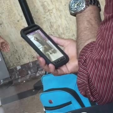 An old man watches a young woman dance on phone