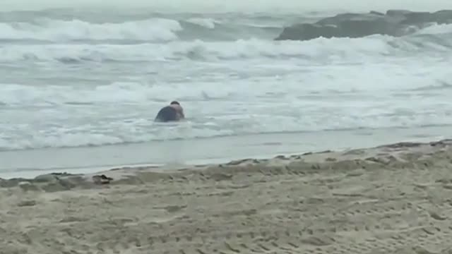 Guy sitting in shallow water beach ocean yellow surfboard