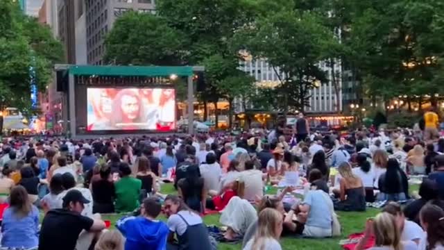 An open-air movie in a park in new york is crowded with people.