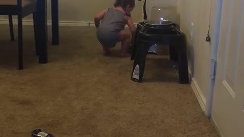 Baby tries filling dog bowl with water using only her hand