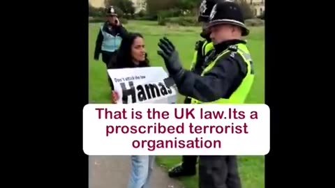 A woman is peacefully holding a sign saying ＂Hamas Is Terrorist＂. Masonic UK Police Clowns