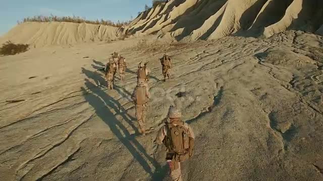 Flying over Group of Running Soldiers in Desert Environment