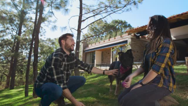 Man and woman playing with a dog in a garden