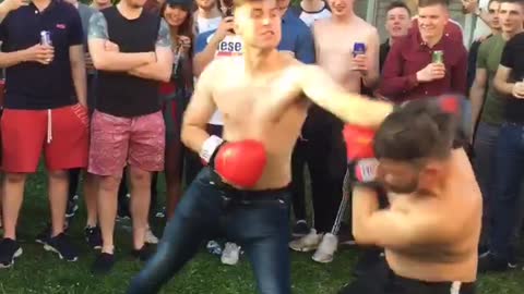 Guy in black pants boxing other guy outside