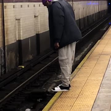 Man hangs his toes over the edge of subway train platform