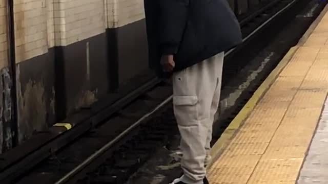 Man hangs his toes over the edge of subway train platform