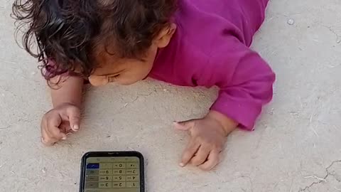 A baby is playing with mobile very funny
