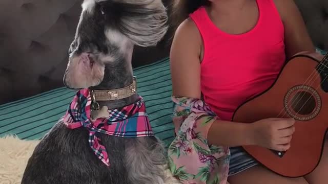 Black white dog howls while girl in pink shirt sings