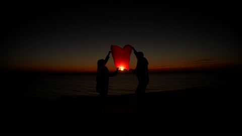 Lovers launch a paper lantern into the sky