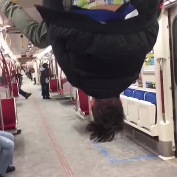 Man hanging and flipping from bar on train