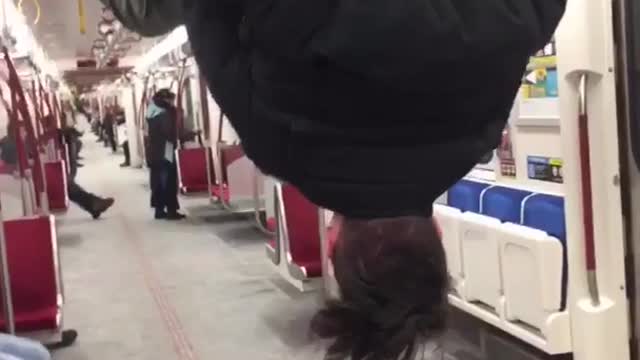 Man hanging and flipping from bar on train