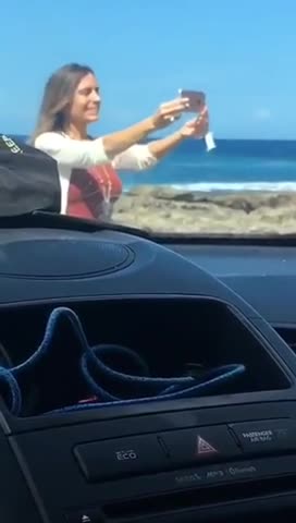 Girl with pink iphone takes selfies on beach