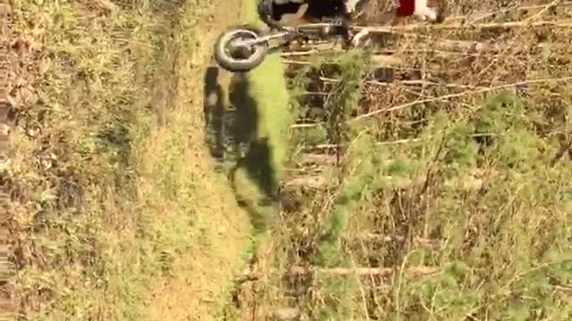 Red shirt guy tries to jump motorcycle dirt ramp and falls in grass