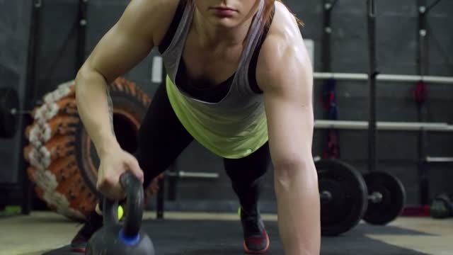 Girl lifting kettlebell in push up position.