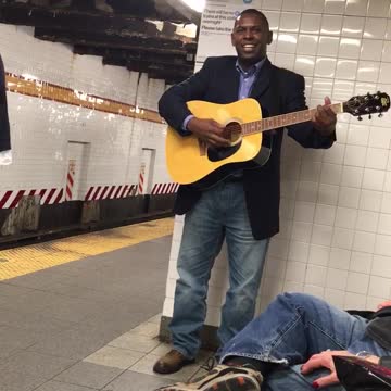 Man in blue suit playing guitar in station