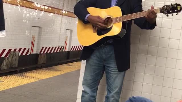 Man in blue suit playing guitar in station