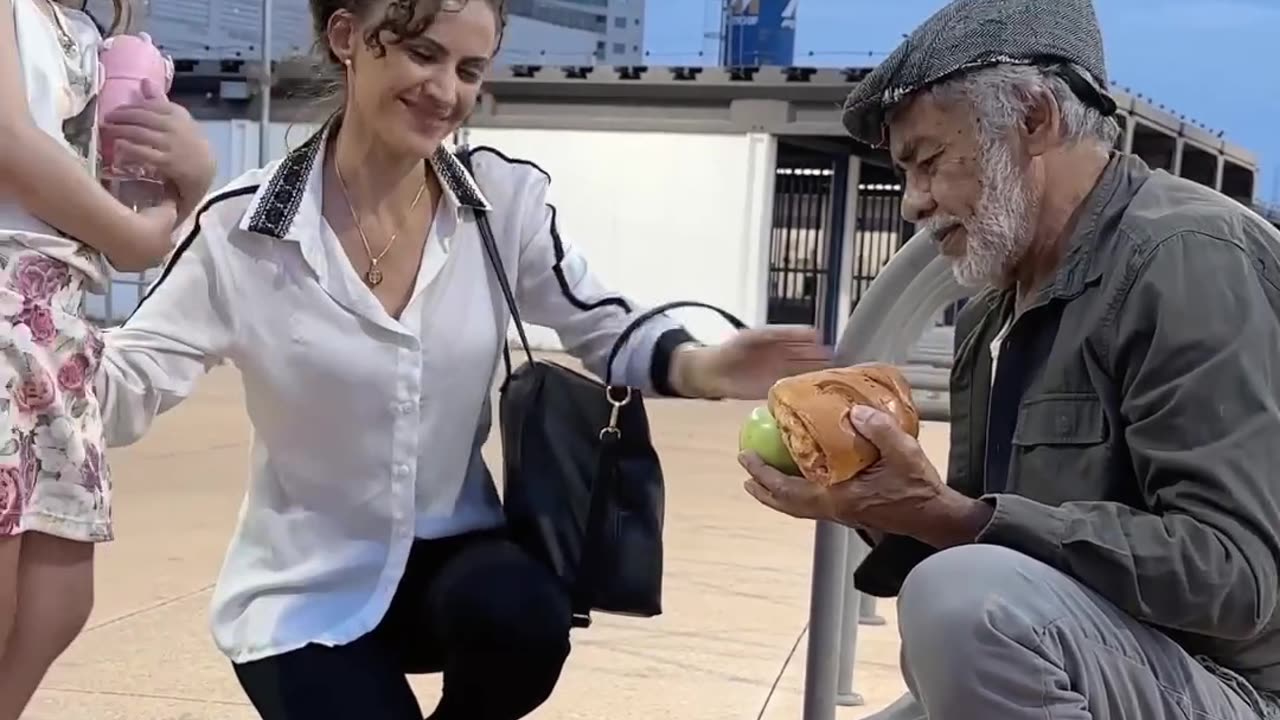 A mother and daughter extend a helping hand to a homeless man