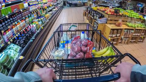 adult male pushing a metal shopping cart through the produce section of a supermark free stock video