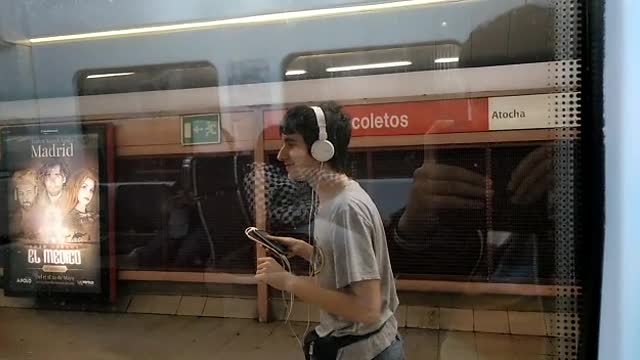 Guy grey shirt white headphones runs along with subway
